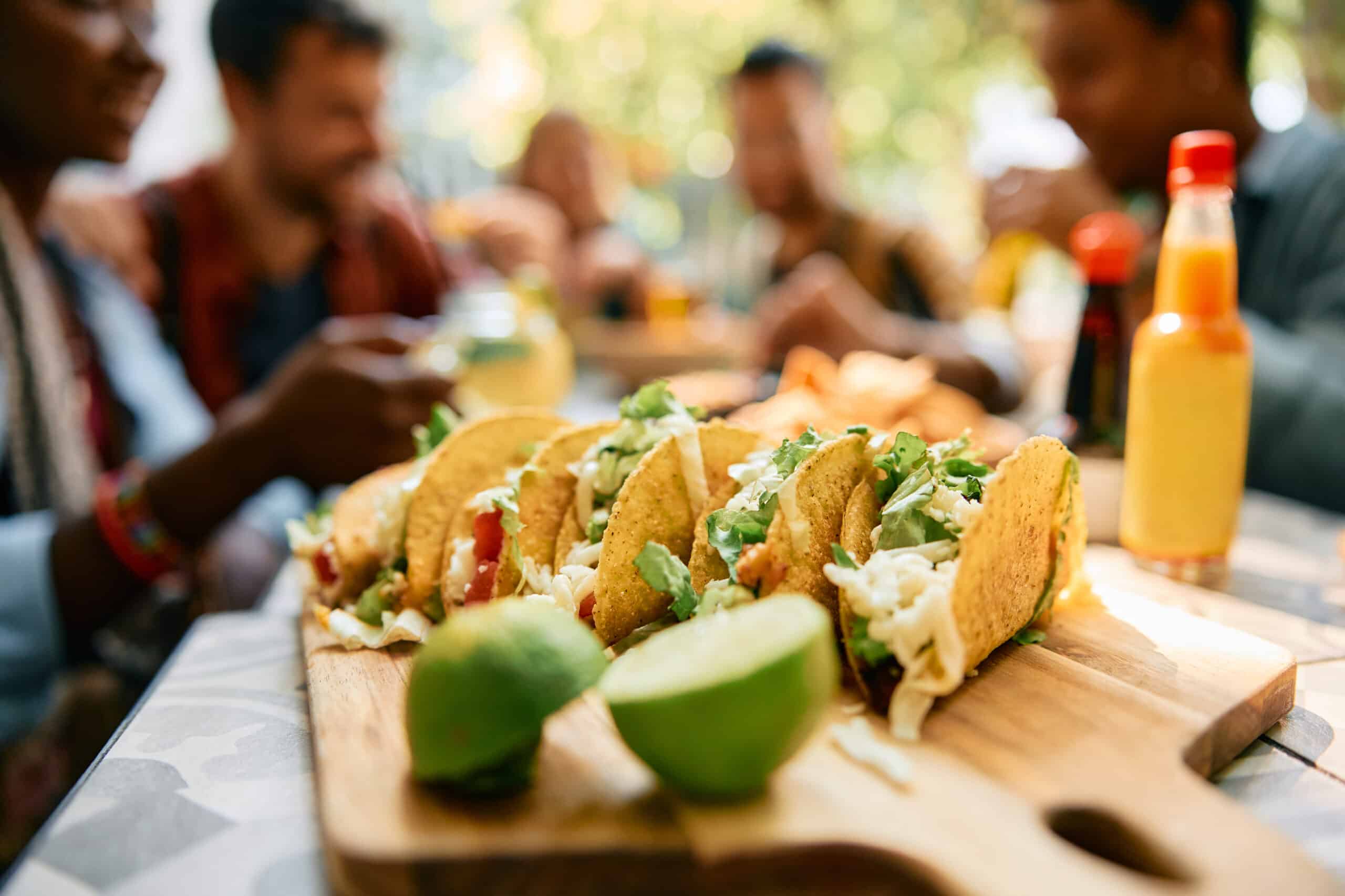 gros plan sur des tacos avec un groupe d'amis en l'arrière-plan