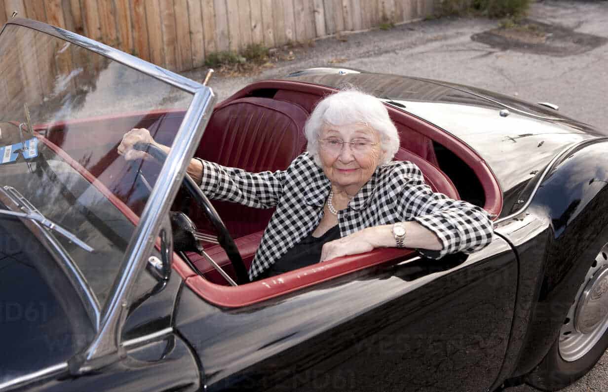 smiling older woman driving convertible